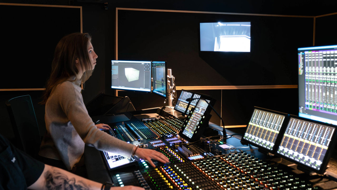 An image of a student working on a mixing board in an editing suite